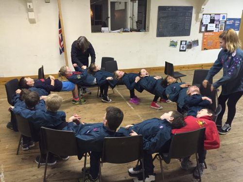 The troop using the chairs in a 'Circle of Trust' exercise